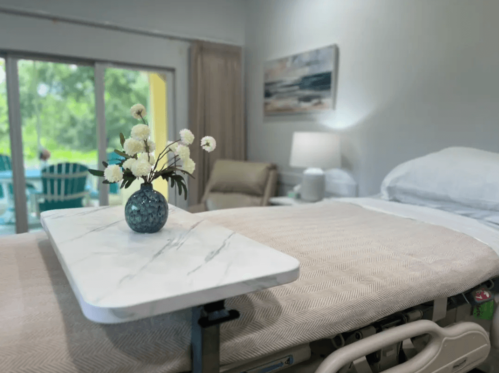 Sunlit inpatient room with fresh flowers on the bedside table